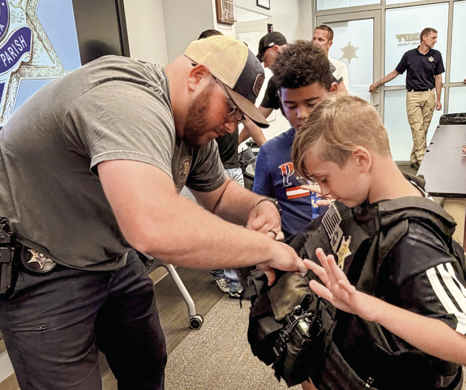 SBSO Narcotics Agent Rhett Fleetwood helps a Junior Deputy try on a protective law enforcement vest.