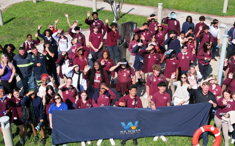 Seniors, juniors, and some faculty of Chalmette High School wave in a photo with various Maritime leaders, including the St. Bernard Port and Associated Terminals.