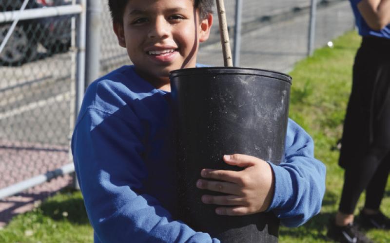 5th grader Adolfo Lopez Lopez holding a tree.