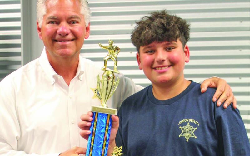 St. Bernard Sheriff James Pohlmann presents 2024 Junior Deputy Academy graduate Carter Blanchard with a trophy for being named Top Shooter on range day.