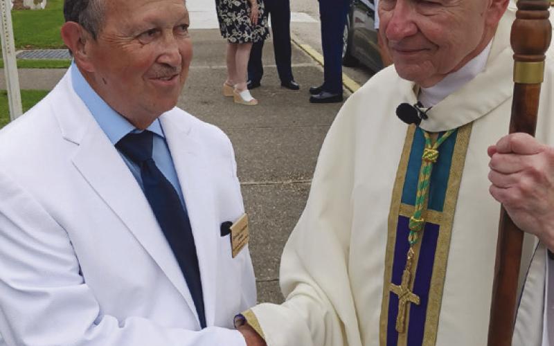 Sterling Constant, an usher at Prompt Succor church, greets Archbishop Gregory Aymond. Photo by Jimmy Delery