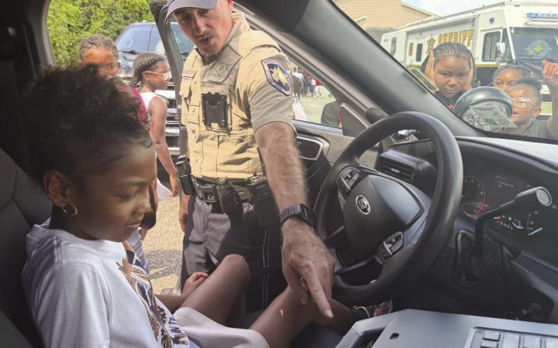 Dep. David Woodru of the Field Operations Bureau shows Christian Fellowship Church’s Camp Conquer Summer Camp participants how the sirens in his patrol unit work.