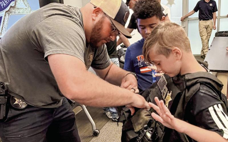 SBSO Narcotics Agent Rhett Fleetwood helps a Junior Deputy try on a protective law enforcement vest.