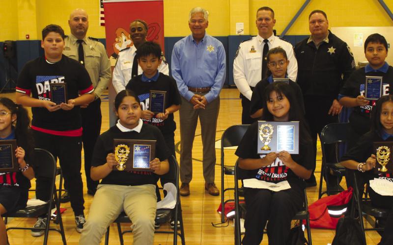 Chalmette Elementary School fifth graders named SBSO D.A.R.E. program essay winners are first row, from left: Arianny Sanchez, Hazel Villalta, Julia Magundayao and Gianna Pacheco. Second-place essay contest winners are, second row, from left: Keylor Stephens, Rain Luis, Maria Da Silva and Nathan Escobar. With the winners are, third row, from left: Lt. Brad Nuccio, Capt. Lisa Jackson, Sheri James Pohlmann, Col. Daniel Bostic and Sgt. Brandon Lewis.