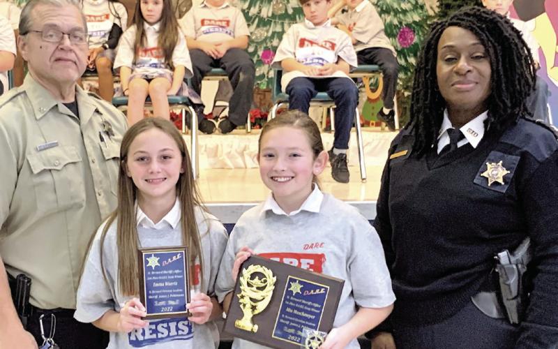 St. Bernard Christian Academy held a graduation Dec. 15 for fifth graders who graduated from the St. Bernard Sheriff’s Office D.A.R.E. program. Essay contest winners are, from left: Emma Wuertz, runner-up, and Mia Maschmeyer, first place. Also pictured are: Sgt. Darrin Miller, far left, and Capt. Lisa Jackson, far right.
