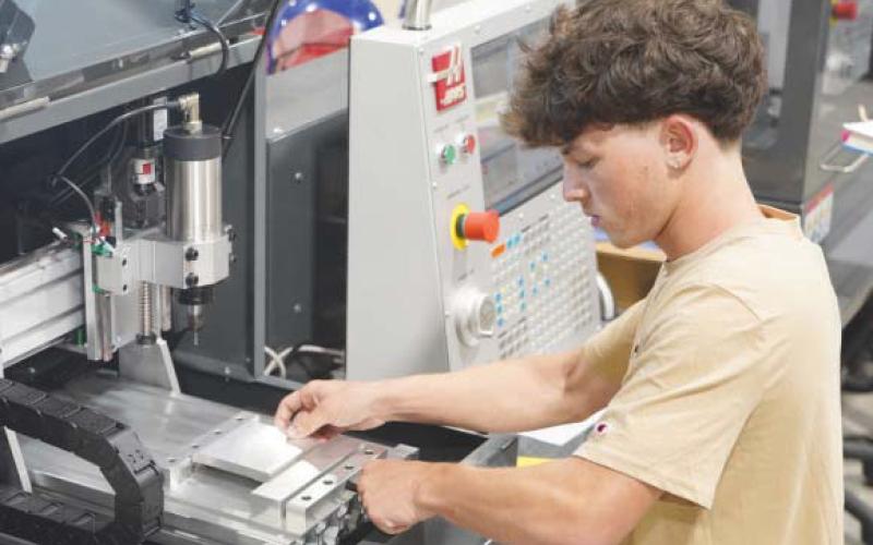 Jeremy Toledo, a student in Nunez Community College’s Machinist program, secures a piece of metal in a tabletop CNC router in preparation for precision cutting. High-tech workforce programs like the Machinist program, which lead to high-wage, high-demand careers, have played a part in driving historic enrollment increases at the Chalmette college.