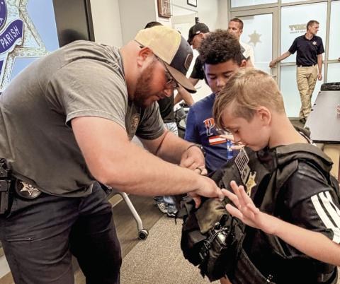 SBSO Narcotics Agent Rhett Fleetwood helps a Junior Deputy try on a protective law enforcement vest.