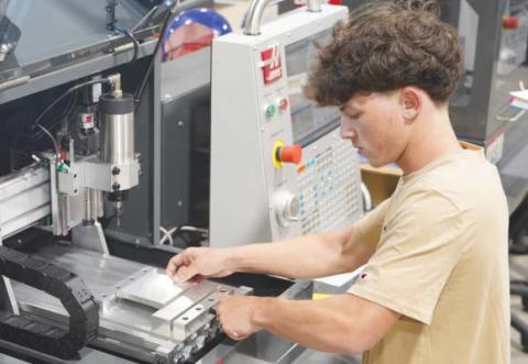 Jeremy Toledo, a student in Nunez Community College’s Machinist program, secures a piece of metal in a tabletop CNC router in preparation for precision cutting. High-tech workforce programs like the Machinist program, which lead to high-wage, high-demand careers, have played a part in driving historic enrollment increases at the Chalmette college.