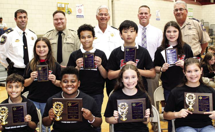 Arabi Elementary School fifth graders named St. Bernard Sheriff’s Office D.A.R.E. program first-place essay contest winners are, first row, from left: David Lourenco, Cambryn Dotson, Kinsley Nation and Ava Bella Vandenborre. Second-place winners are second row, from left: Mia Heffker, Elijah Petty, Quot-Viet Nguyen and Hayden Davis. With the winners are, third row, from left: Capt. Matthew Arcement, Sgt. Brandon Lewis, Sheriff James Pohlmann, Maj. Daniel Bostic and Lt. Robert Broadhead.